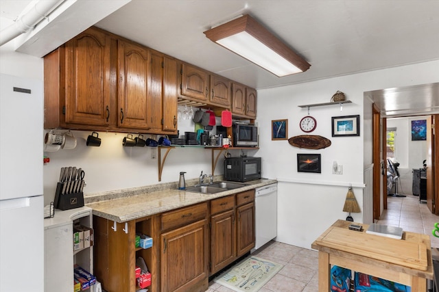 kitchen featuring white appliances, sink, and light tile patterned floors