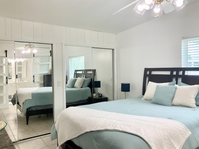 bedroom with multiple closets, vaulted ceiling, and light tile patterned floors