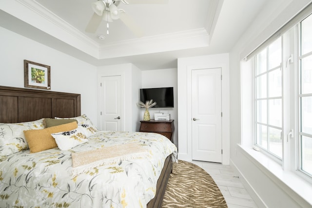 bedroom featuring multiple windows, crown molding, and a tray ceiling