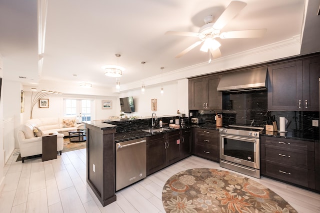 kitchen with appliances with stainless steel finishes, decorative light fixtures, sink, kitchen peninsula, and wall chimney range hood