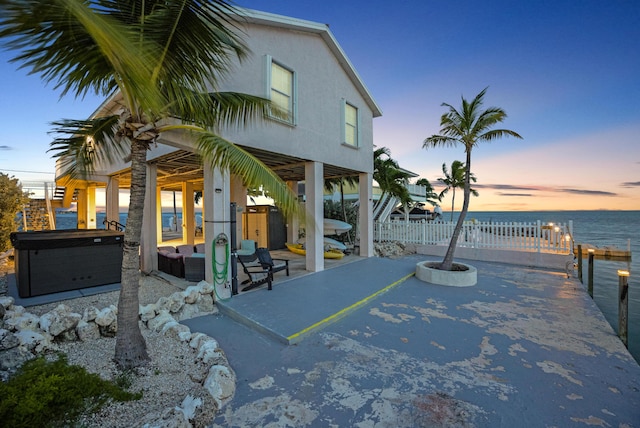 exterior space featuring a water view, a hot tub, and outdoor lounge area