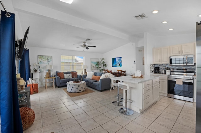 kitchen featuring lofted ceiling with beams, light tile patterned floors, appliances with stainless steel finishes, a kitchen breakfast bar, and kitchen peninsula