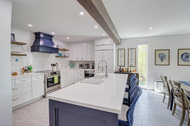 kitchen featuring stainless steel electric stove, light countertops, custom range hood, beam ceiling, and open shelves