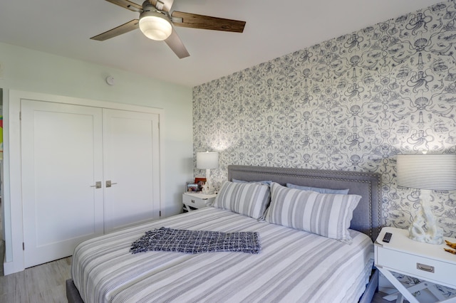 bedroom featuring a closet, wallpapered walls, a ceiling fan, and wood finished floors