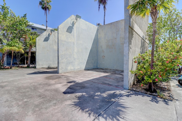 view of side of home featuring stucco siding and a gate