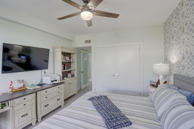 bedroom with light wood-type flooring, visible vents, a closet, and ceiling fan