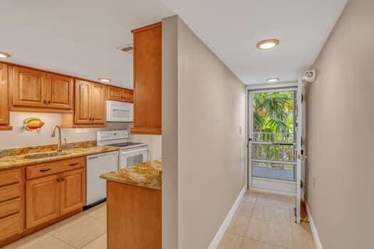 201 E Ocean Dr Unit 211, Key Colony, FL 33051 - kitchen with white appliances, a sink, light stone counters, light tile patterned flooring, and baseboards