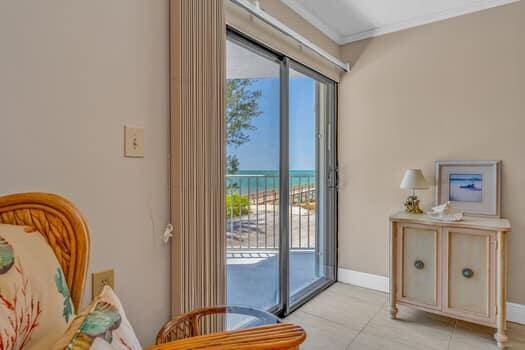 201 E Ocean Dr Unit 211, Key Colony, FL 33051 - doorway with view of water and beach, light tile patterned floors, ornamental molding, and baseboards