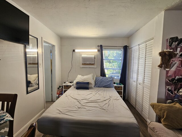 bedroom with a wall mounted air conditioner and a textured ceiling