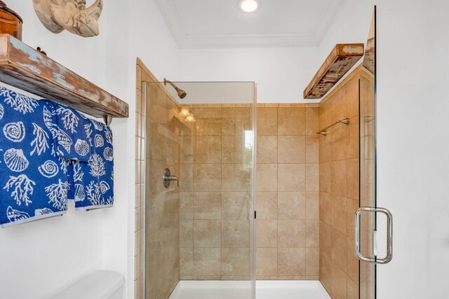 bathroom with ornamental molding, toilet, and a shower with door