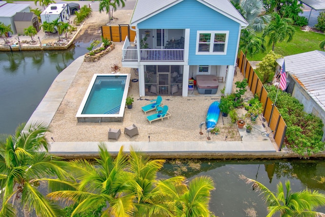 rear view of property with a balcony, a water view, a sunroom, and a patio area