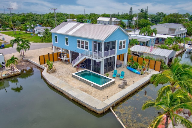 back of house featuring a water view, a sunroom, and a patio area