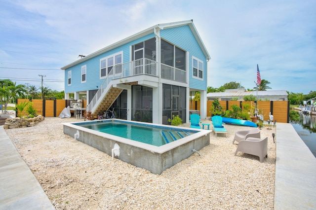 rear view of property with a fenced in pool, a patio area, and a sunroom