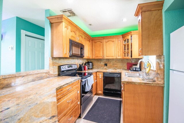 kitchen with light stone counters, sink, decorative backsplash, and black appliances