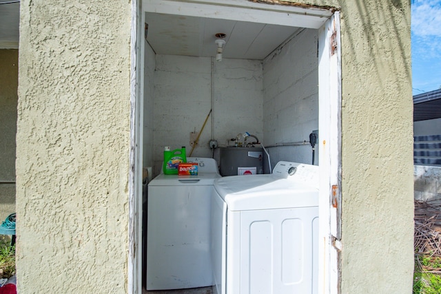 clothes washing area featuring water heater and separate washer and dryer