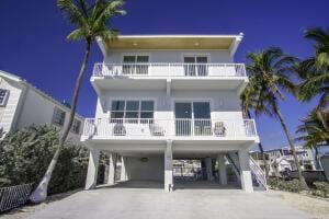 raised beach house featuring a balcony, driveway, and a carport