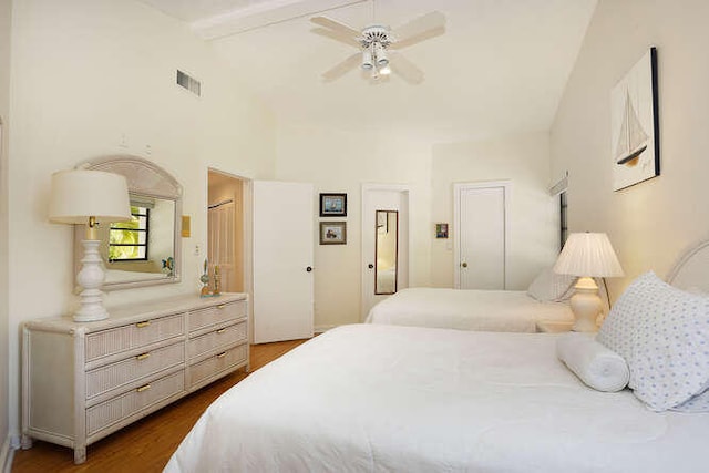 bedroom with hardwood / wood-style flooring, connected bathroom, ceiling fan, and beamed ceiling