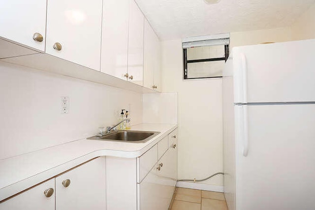 kitchen featuring white cabinetry, sink, light tile patterned floors, and white refrigerator