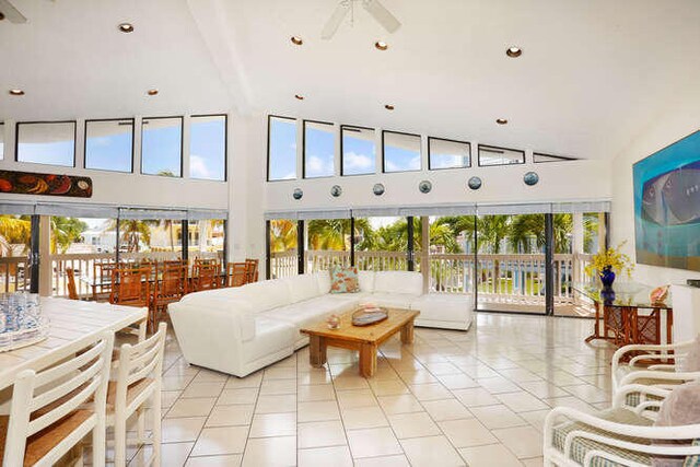 living room featuring light tile patterned flooring, high vaulted ceiling, and ceiling fan