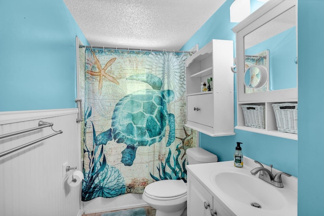 full bathroom with shower / bath combo with shower curtain, vanity, toilet, and a textured ceiling