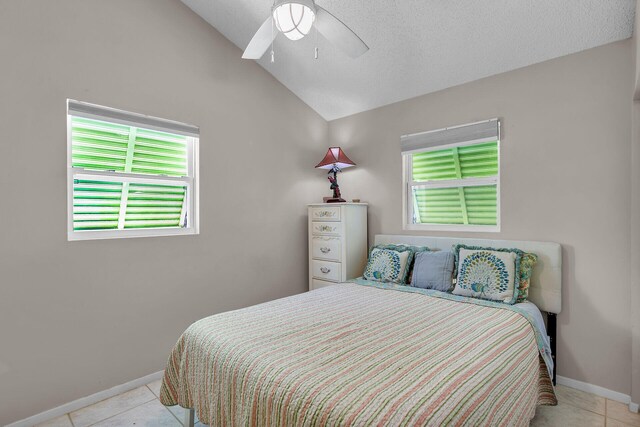 bedroom featuring ceiling fan, vaulted ceiling, a textured ceiling, and light tile patterned flooring