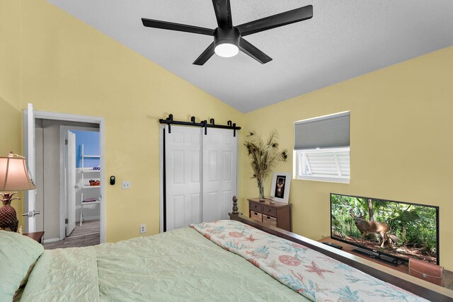 bedroom featuring lofted ceiling, a closet, a barn door, and ceiling fan