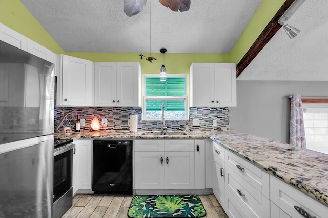 kitchen with white cabinetry, black dishwasher, sink, and stainless steel refrigerator