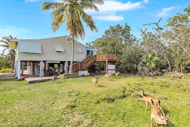 rear view of property featuring a deck, a patio area, and a lawn