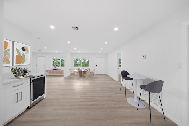 kitchen with wine cooler, light wood-style flooring, white cabinets, recessed lighting, and baseboards