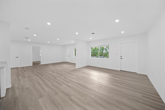 unfurnished living room with light wood finished floors, recessed lighting, and baseboards