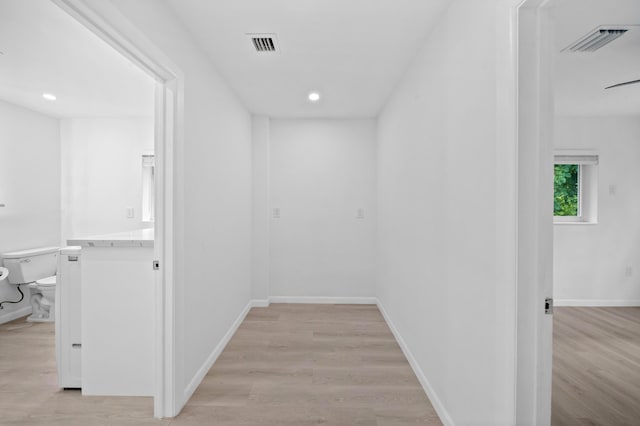 hall featuring light wood-type flooring, recessed lighting, and baseboards