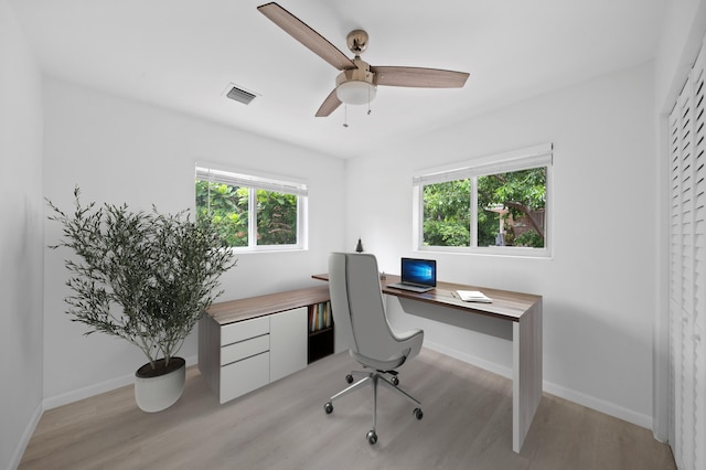 office area with light wood finished floors, healthy amount of natural light, a ceiling fan, and baseboards