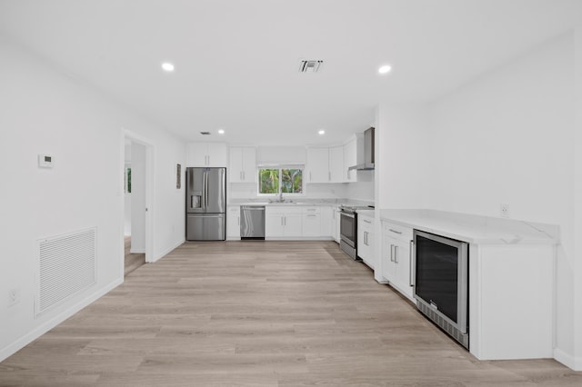 kitchen featuring stainless steel appliances, wall chimney exhaust hood, beverage cooler, a sink, and recessed lighting