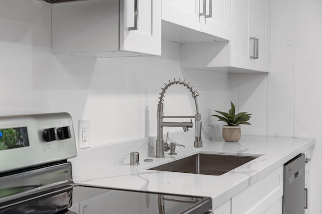 kitchen with a sink, white cabinetry, stainless steel appliances, and light stone counters