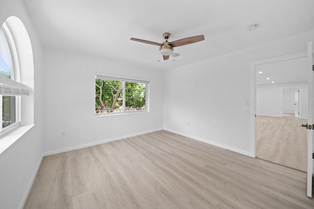 spare room with ceiling fan, light wood finished floors, and baseboards