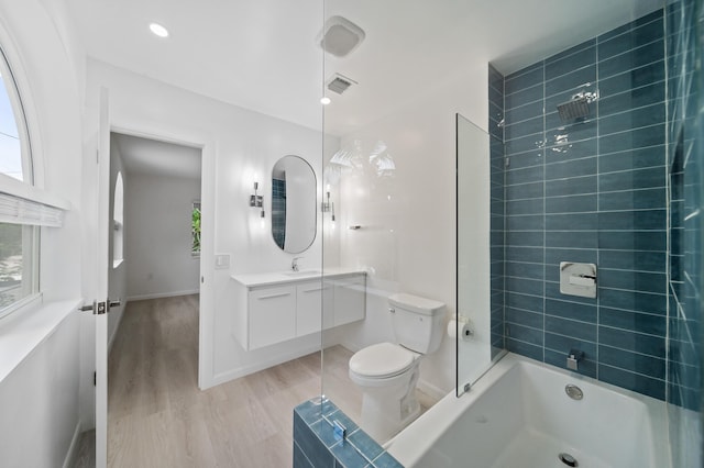 bathroom featuring wood finished floors, shower / bathtub combination, toilet, vanity, and baseboards