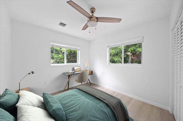 bedroom with multiple windows, wood finished floors, and baseboards