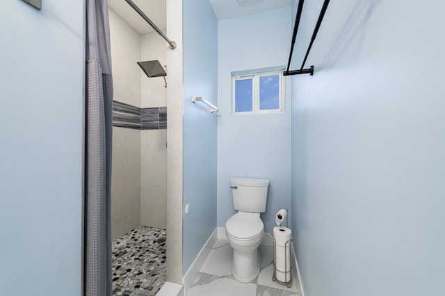full bath with baseboards, a tile shower, and toilet