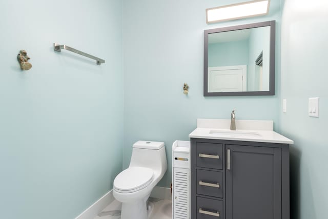 bathroom with marble finish floor, vanity, baseboards, and toilet