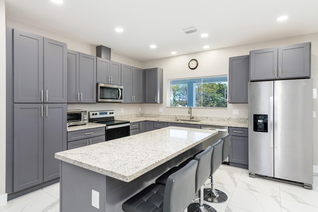 kitchen featuring marble finish floor, appliances with stainless steel finishes, a sink, and gray cabinetry