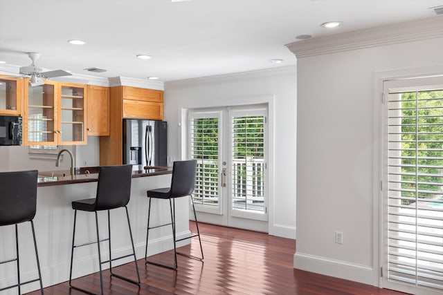413 Emma St Unit A, Key West, FL 33040 - kitchen with stainless steel fridge, a breakfast bar area, black microwave, dark countertops, and glass insert cabinets