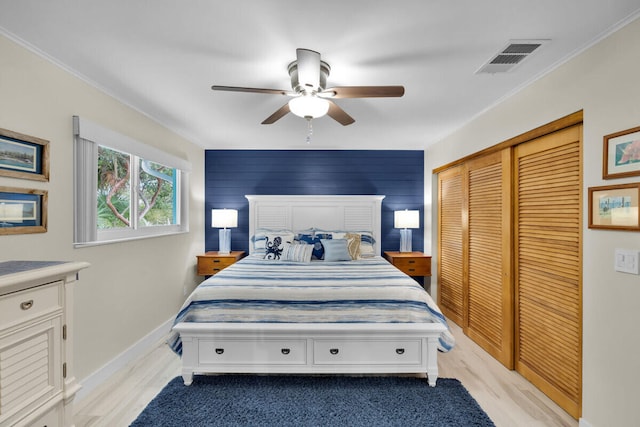 bedroom with ceiling fan, ornamental molding, light wood-type flooring, and a closet