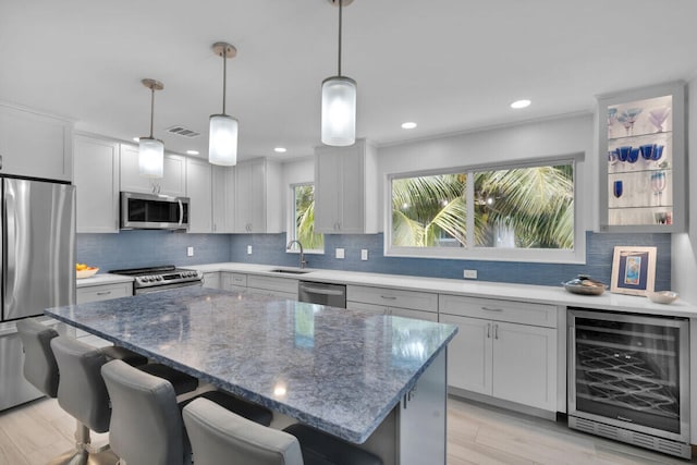 kitchen with wine cooler, pendant lighting, a breakfast bar, and appliances with stainless steel finishes