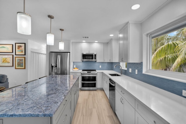 kitchen featuring pendant lighting, sink, white cabinets, a center island, and stainless steel appliances