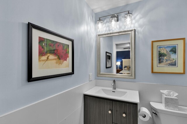 bathroom with vanity, tile walls, and toilet