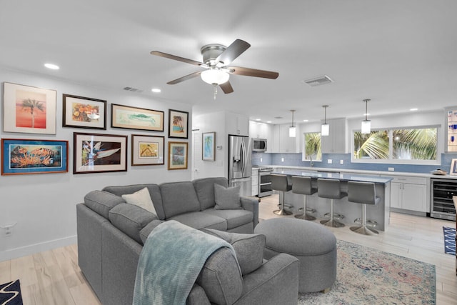 living room featuring wine cooler, ceiling fan, and light hardwood / wood-style floors