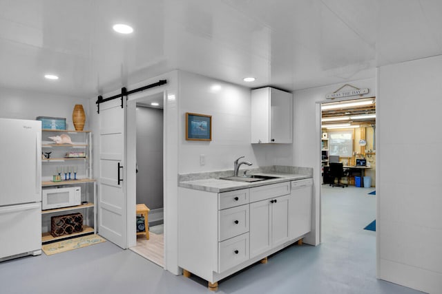 kitchen with white cabinetry, white appliances, a barn door, and sink