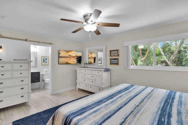 bedroom featuring connected bathroom, light hardwood / wood-style flooring, a barn door, and ceiling fan