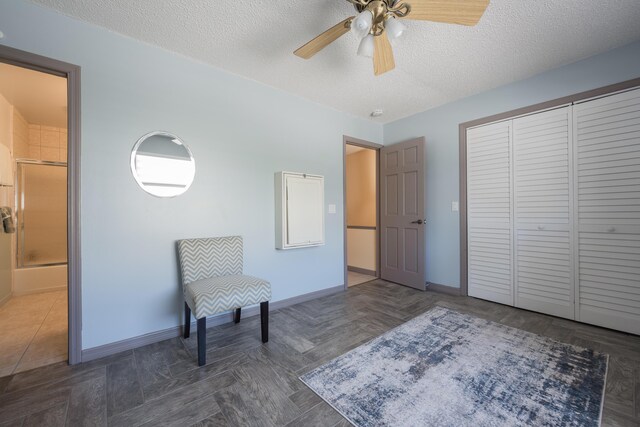 sitting room with ceiling fan, dark parquet flooring, and a textured ceiling