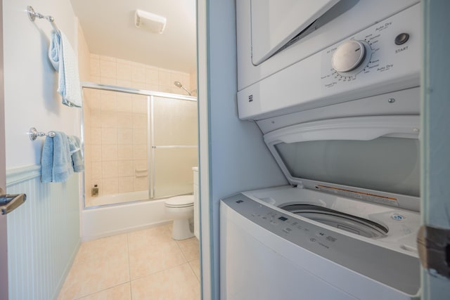 laundry area with stacked washing maching and dryer and light tile patterned floors